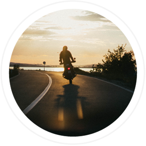 man driving on a motorcycle with sunset in the background