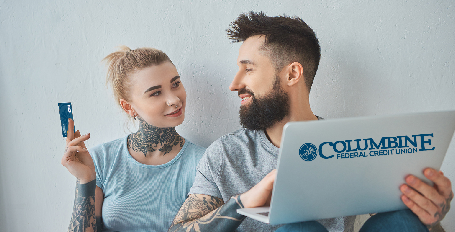 tattooed couple with credit card on computer with logo emblazoned