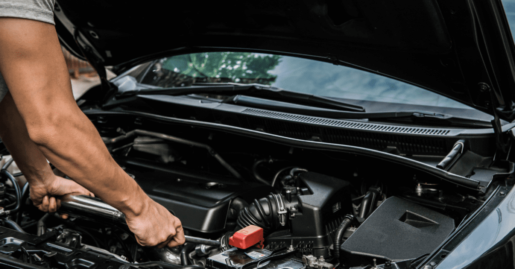 mechanic standing over an engine with an open hood