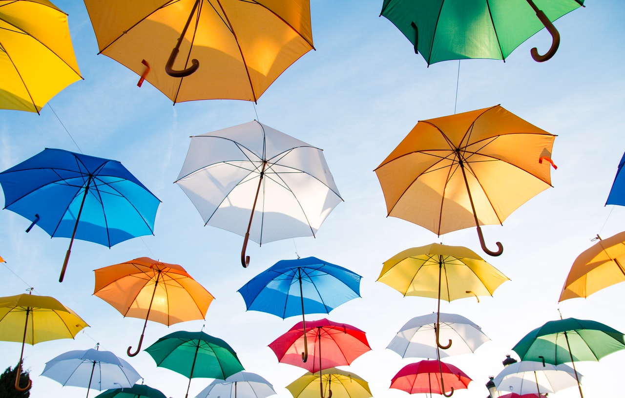 colorful umbrellas hanging above with a view from underneath symbolizing protection