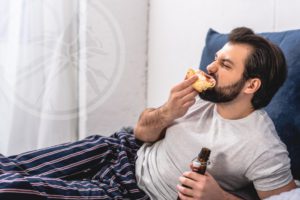 man lounging in pajamas eating and drinking