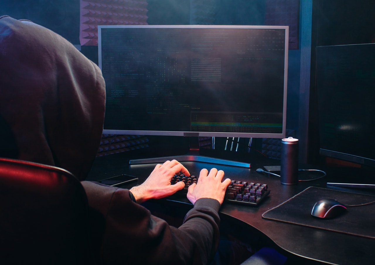 shady character sitting at a computer wearing a hood