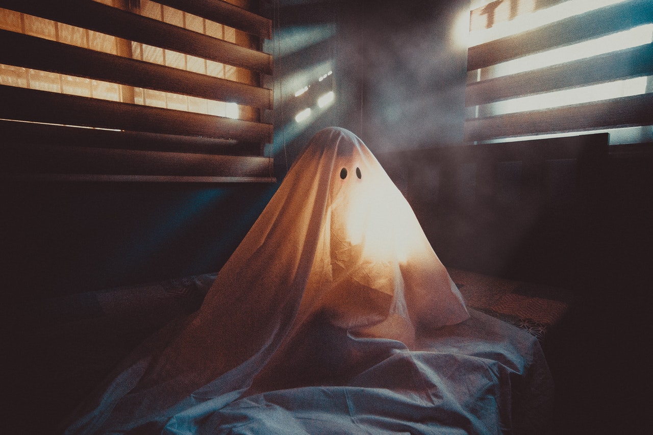 person dressed as a ghost in a creepy dimly lit room