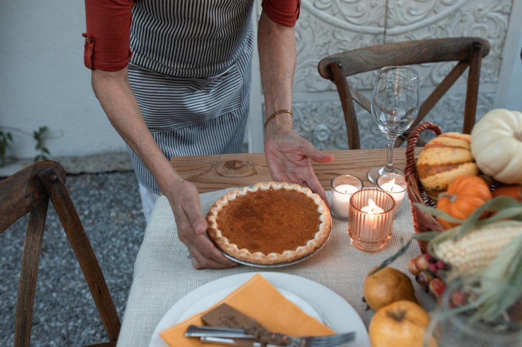 person bringing pie to table on thanksgiving