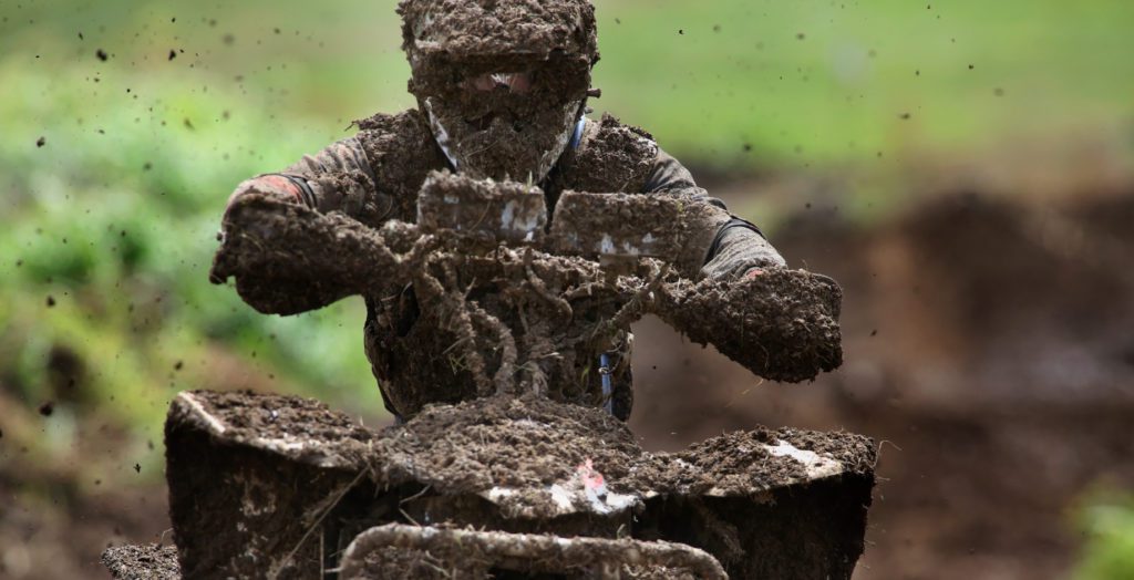person on atv covered in mud