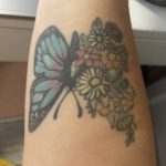 tattoo of a blue butterfly around flowers