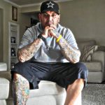 man on a couch with sleeve tattoos and a full leg tattoo