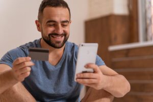 Man smiling holding his card and phone