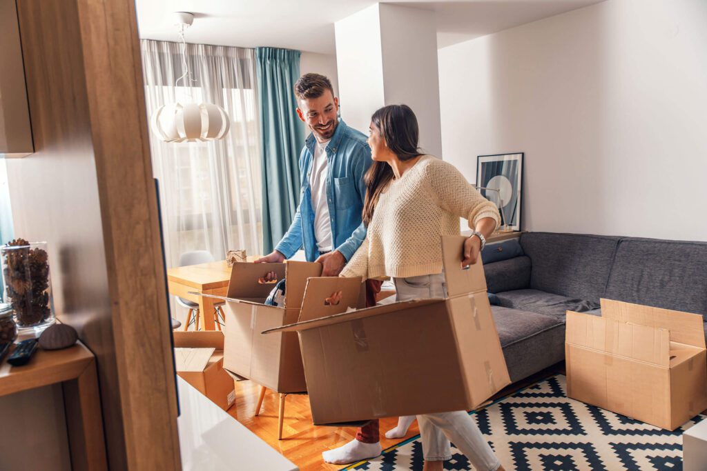 Man and woman packing boxes in living room.