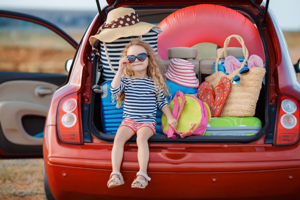 Portrait of a little girl sitting in the trunk of a car
