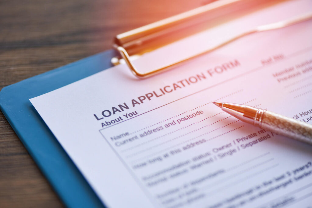 Loan application form attached to clipboard with pen resting on top